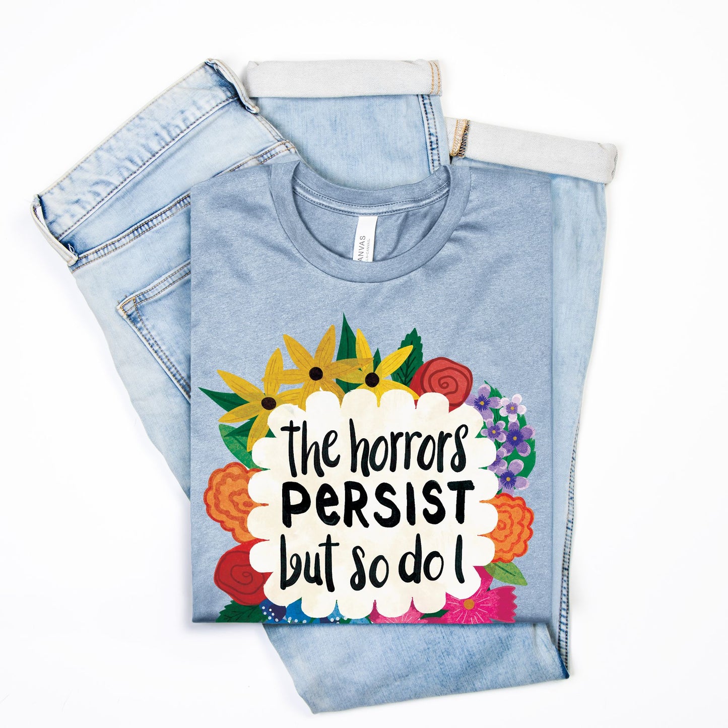 Folded denim pants with a colorful graphic t-shirt with text on a white background