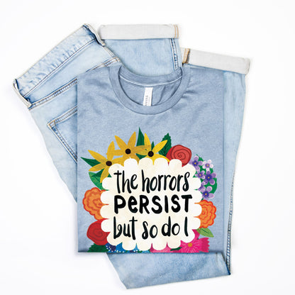 Folded denim pants with a colorful graphic t-shirt with text on a white background